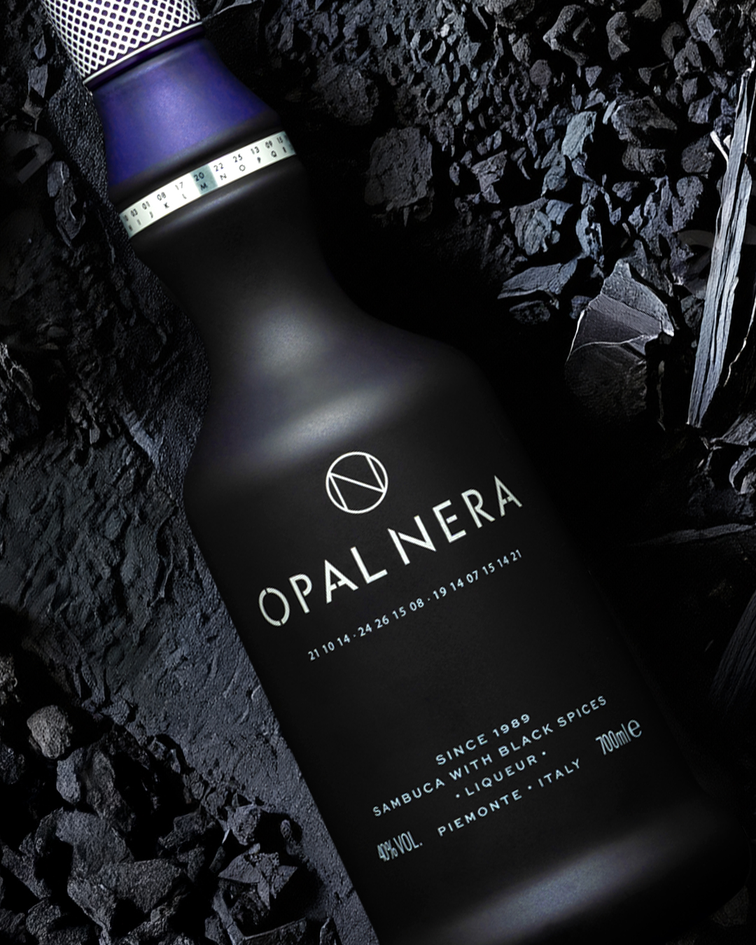 Post social con la bottiglia Opal Nera, sambuca alle spezie nere del Piemonte, su carbone